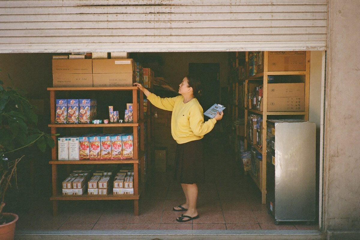 A shop owner checking stock on the shelves of a shophouse unit